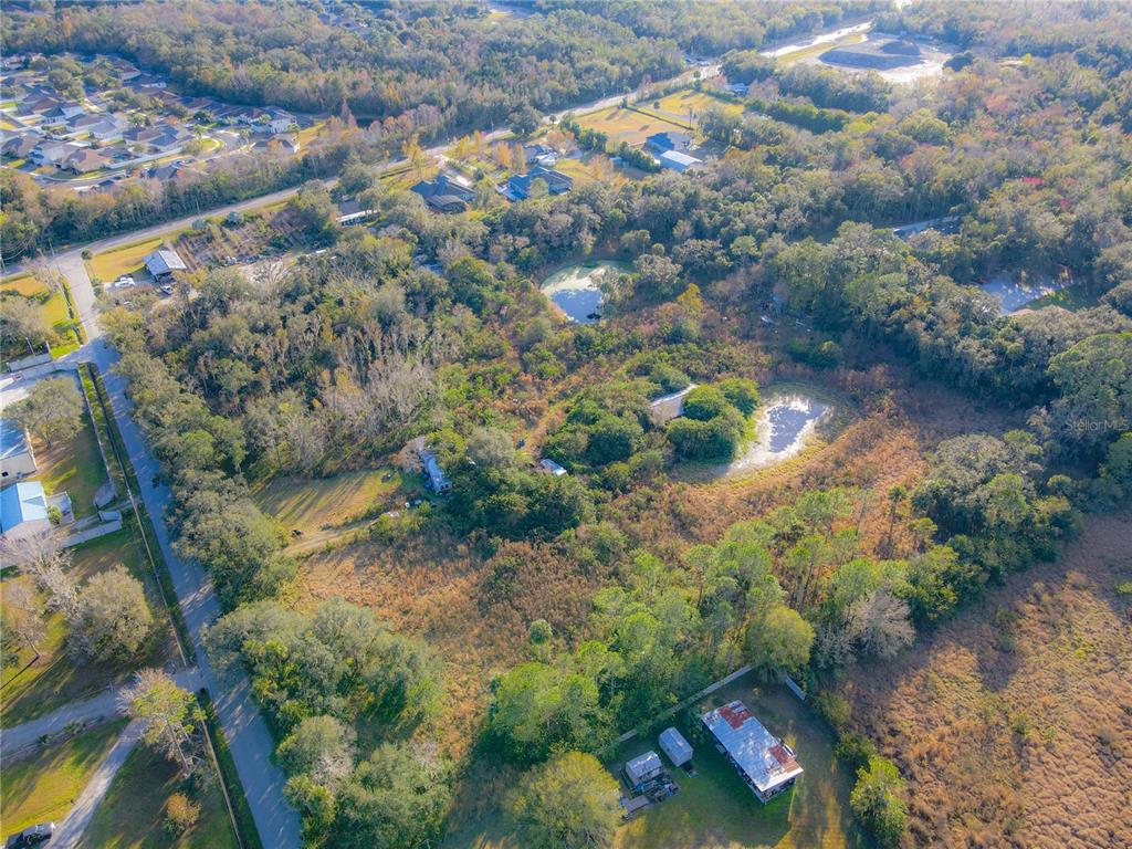 An aerial view shows a rural property with wooded areas, two small ponds, and several buildings — 1050 VAN ARSDALE STREET, OVIEDO, FL