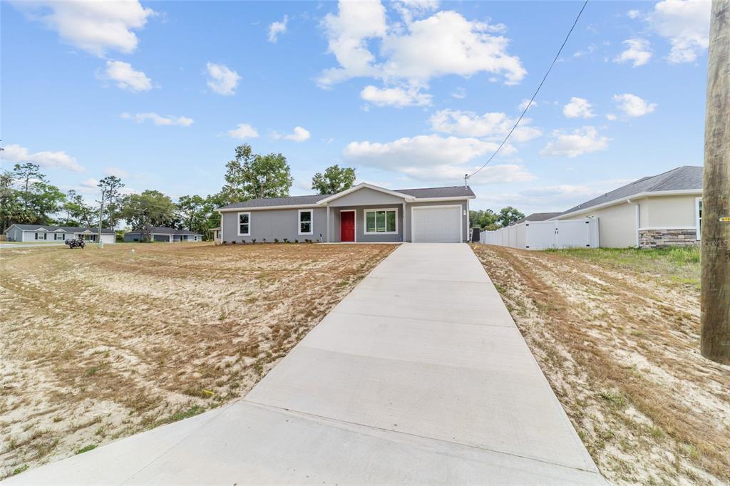 A single-story gray house with a red front door and a concrete driveway — 13078 NE 7TH LOOP, SILVER SPRINGS, FL