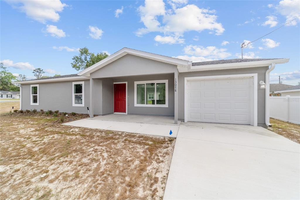 A single-story house with gray siding, a red front door, and an attached one-car garage — 13078 NE 7TH LOOP, SILVER SPRINGS, FL