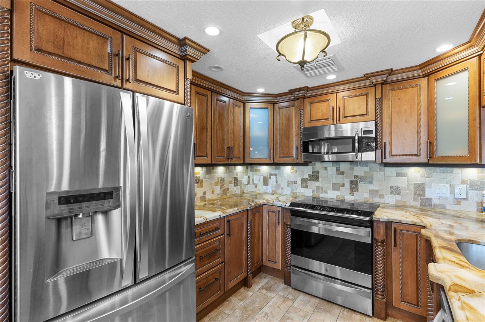 A kitchen features wood cabinets, stainless steel appliances, a tiled backsplash, and granite countertops — 417 Richmond C # 417, Deerfield Beach FL 33442, DEERFIELD BEACH, FL