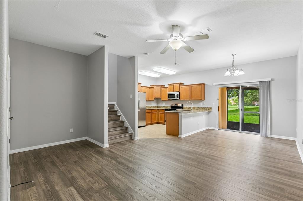 An open-concept living area features wood-look flooring, a staircase, and a kitchen with wooden cabinets — 1220 TWIN TREES LANE, SANFORD, FL