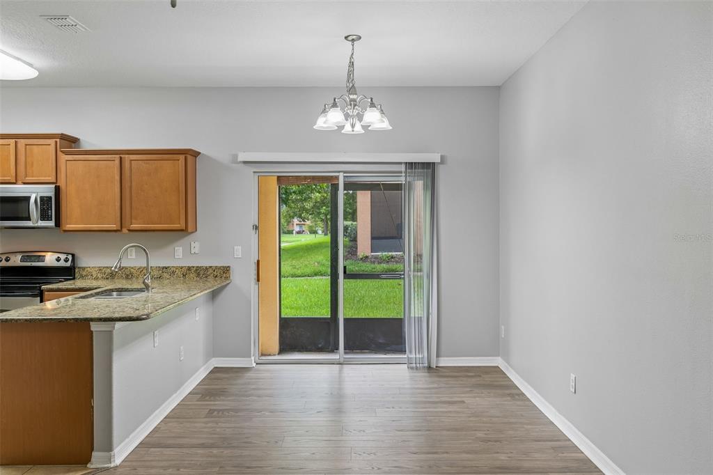 A dining area with wood-look flooring, a chandelier, and a sliding glass door to a patio — 1220 TWIN TREES LANE, SANFORD, FL