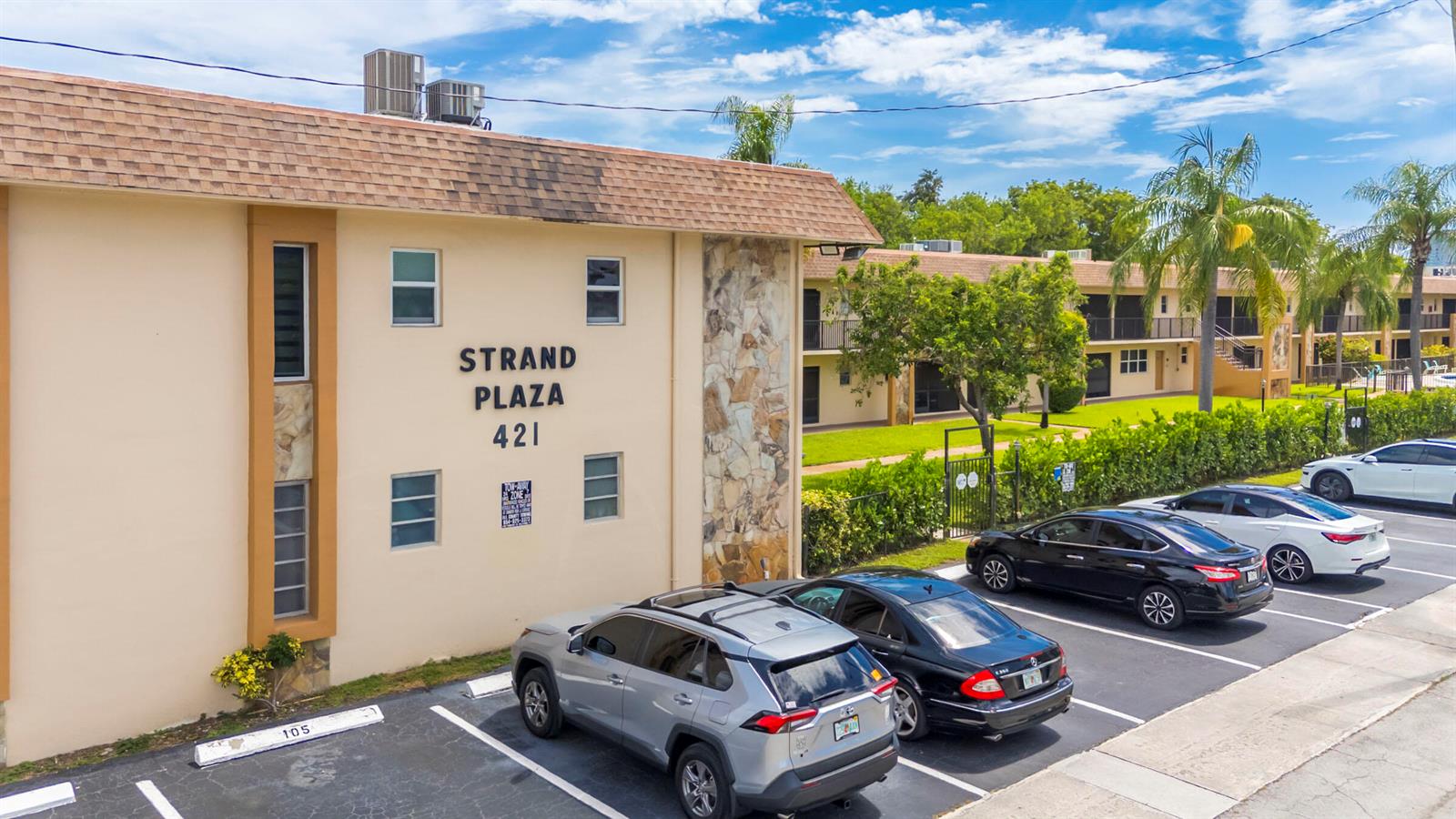 An exterior view of a two-story apartment building with a parking lot in front — 421 NE 1ST Street # 204, Hallandale Beach FL 33009, HALLANDALE BEACH, FL