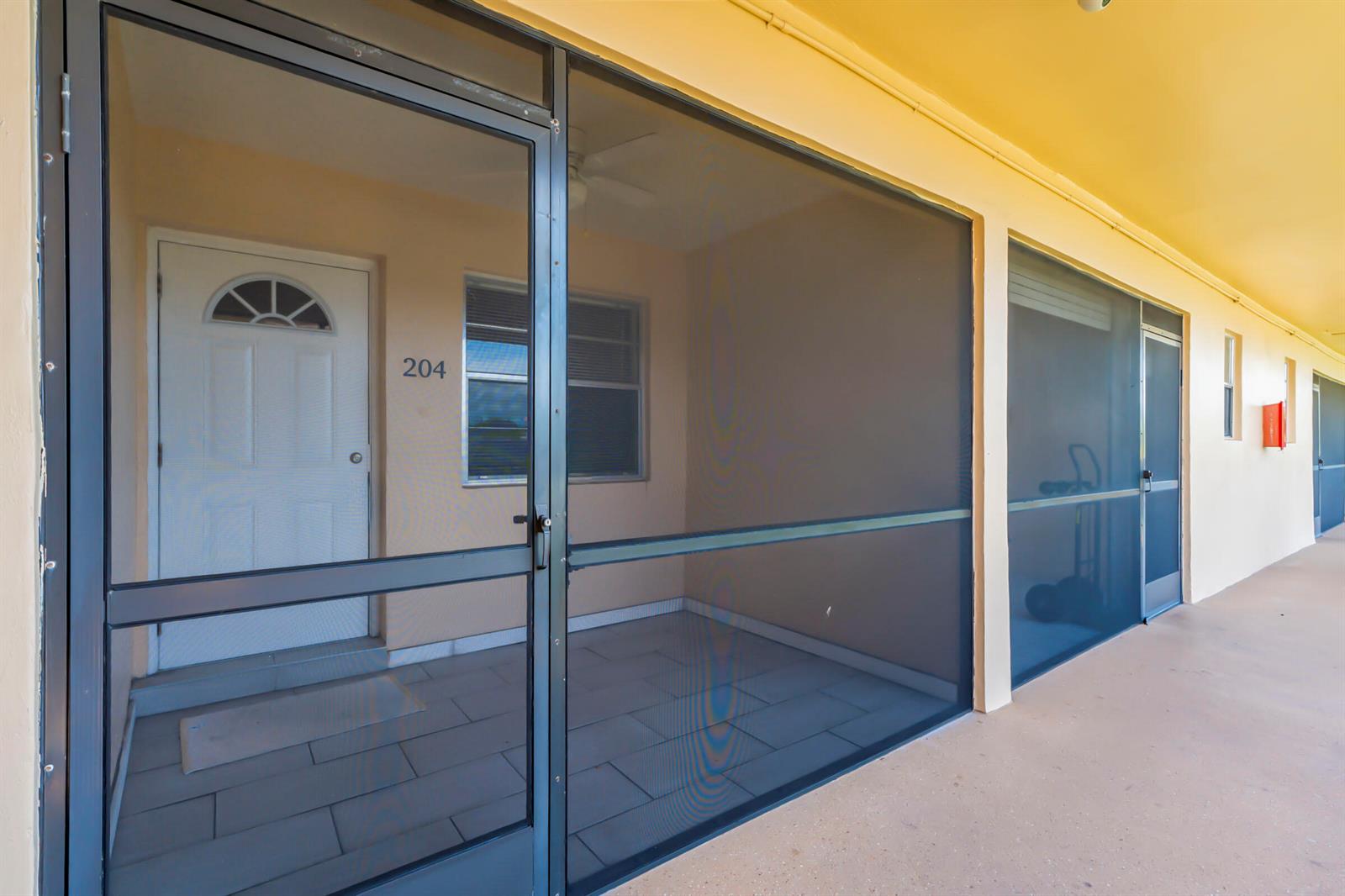A screened-in patio entrance features a white door labeled 204 and tiled flooring — 421 NE 1ST Street # 204, Hallandale Beach FL 33009, HALLANDALE BEACH, FL
