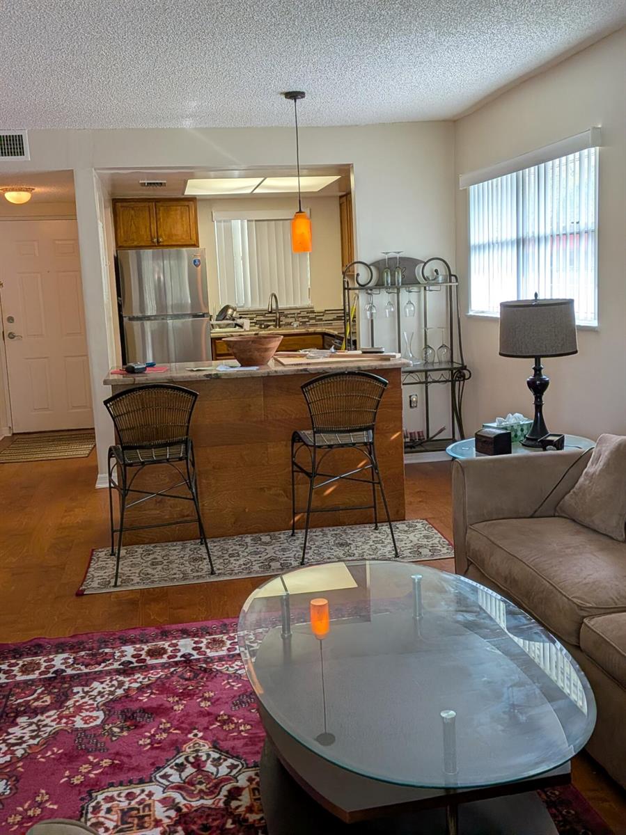 An open-concept kitchen with a breakfast bar overlooks a living room with a patterned rug — 4141 16th Street, Vero Beach FL 32960, VERO BEACH, FL