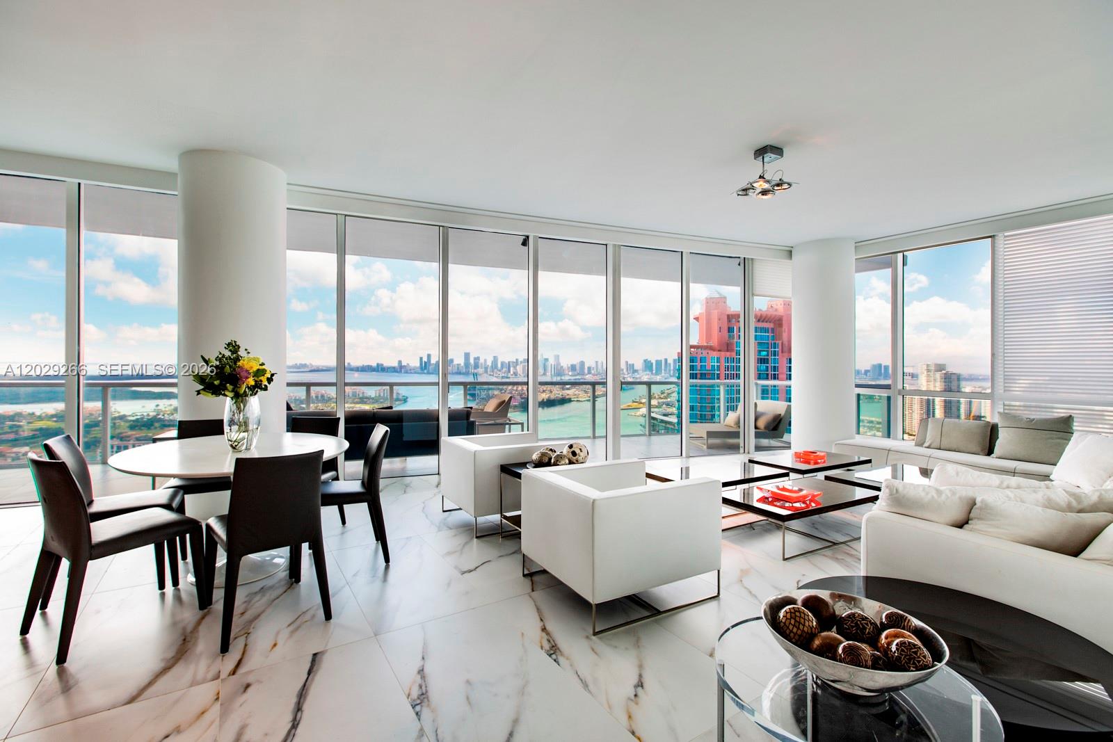 A modern living and dining area features marble floors, white furniture, and floor-to-ceiling windows — 100 S Pointe Dr # 3701, Miami Beach FL 33139, MIAMI BEACH, FL