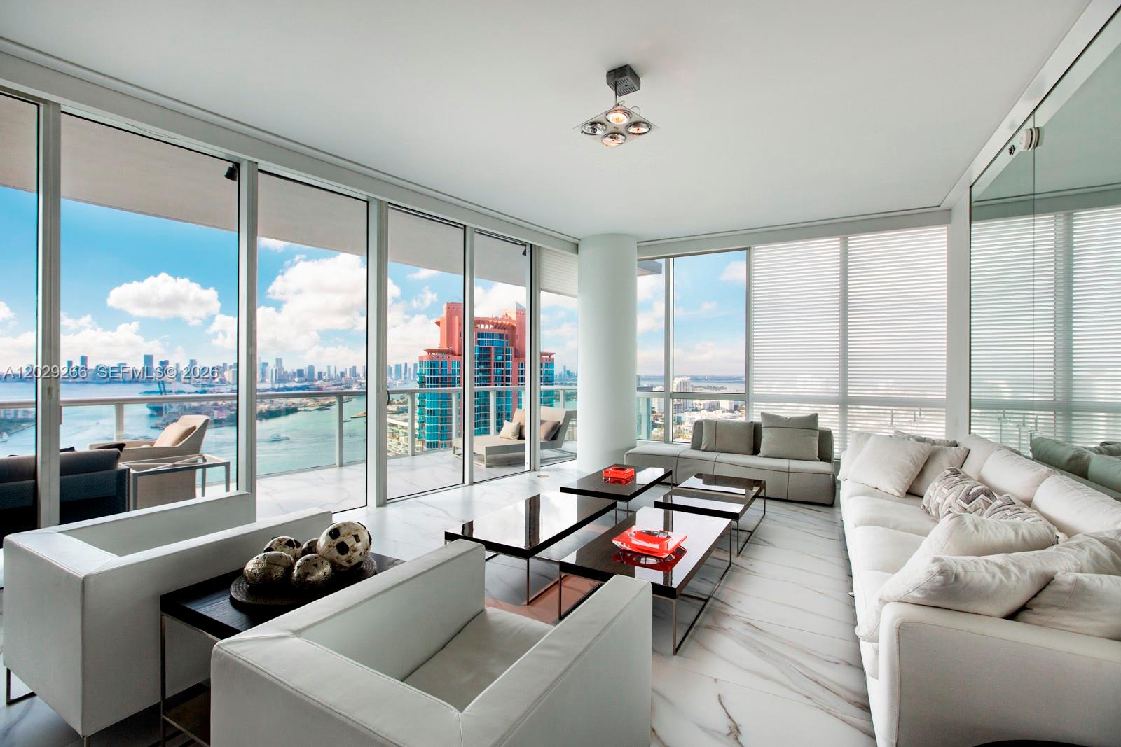 A modern living room with white marble floors, floor-to-ceiling windows, and a city skyline view — 100 S Pointe Dr # 3701, Miami Beach FL 33139, MIAMI BEACH, FL