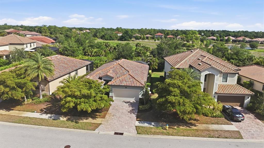 An aerial view shows three suburban houses with tile roofs and driveways along a street — 12540 CANAVESE LANE, VENICE, FL