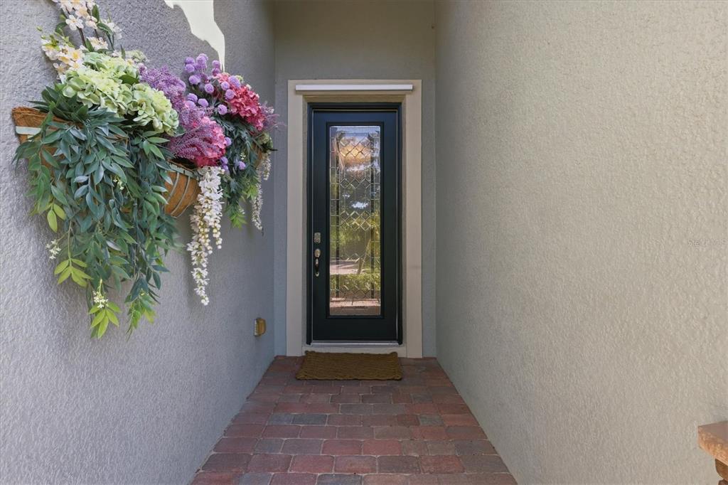 An exterior entryway features a black door with a glass insert and a floral arrangement — 12540 CANAVESE LANE, VENICE, FL