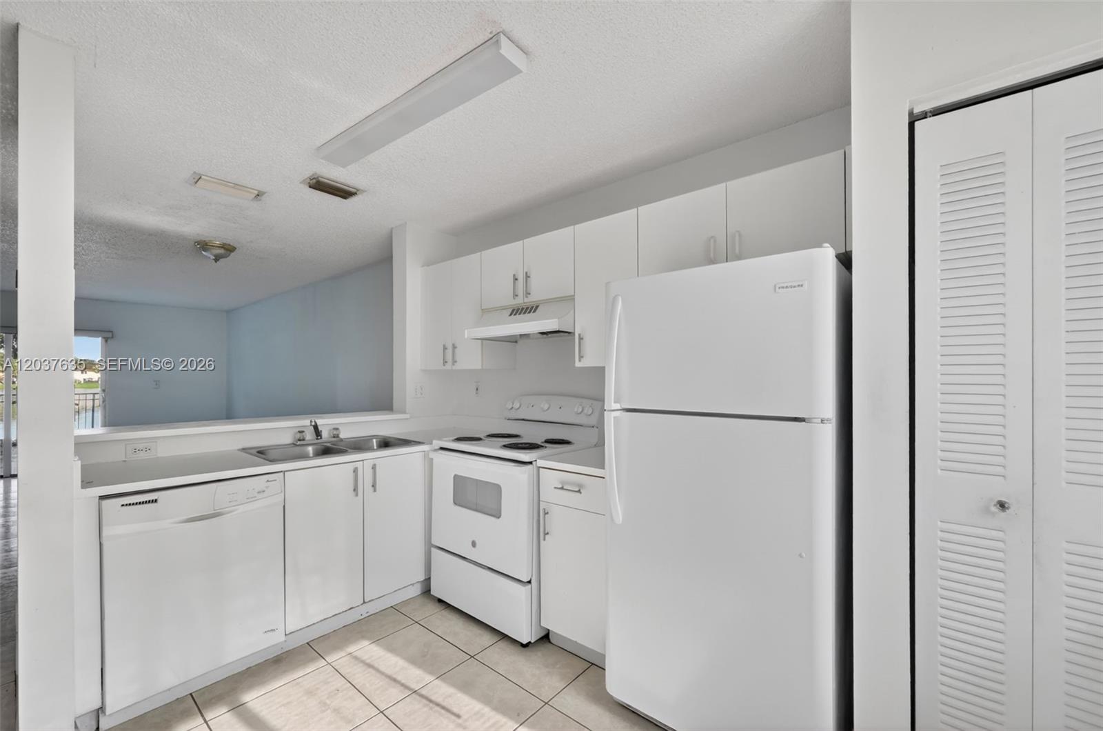 A white kitchen features a refrigerator, stove, dishwasher, and cabinets with tile flooring — 17378 SW 139th Ct, Miami FL 33177, MIAMI, FL
