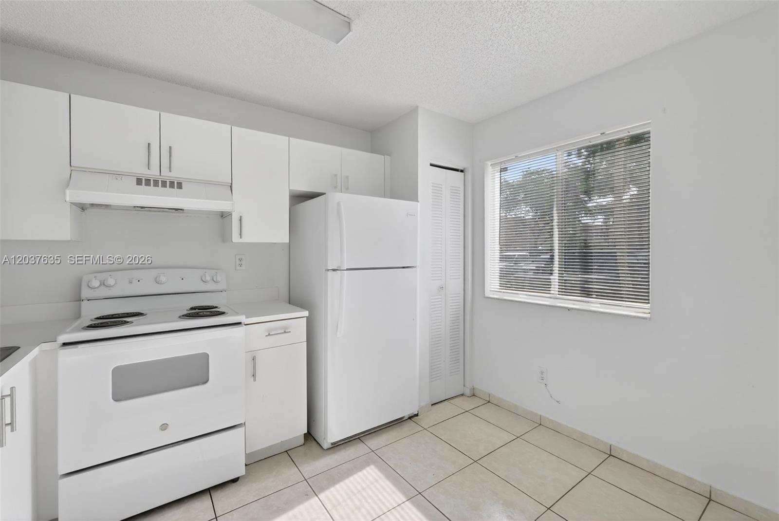 A kitchen features white appliances, white cabinets, and light-colored tile flooring — 17378 SW 139th Ct, Miami FL 33177, MIAMI, FL