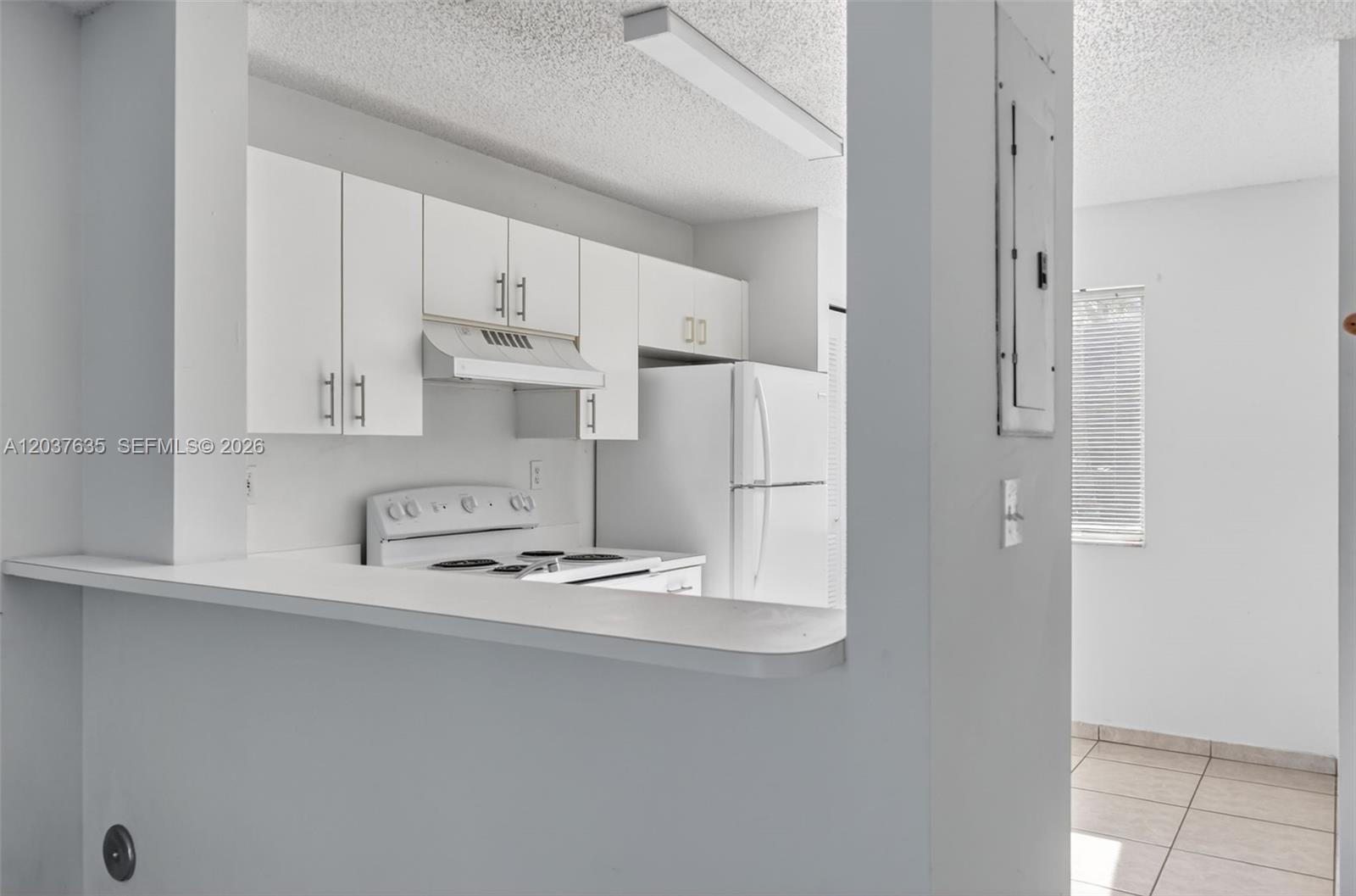 A white kitchen features a pass-through counter, white appliances, and cabinets — 17378 SW 139th Ct, Miami FL 33177, MIAMI, FL