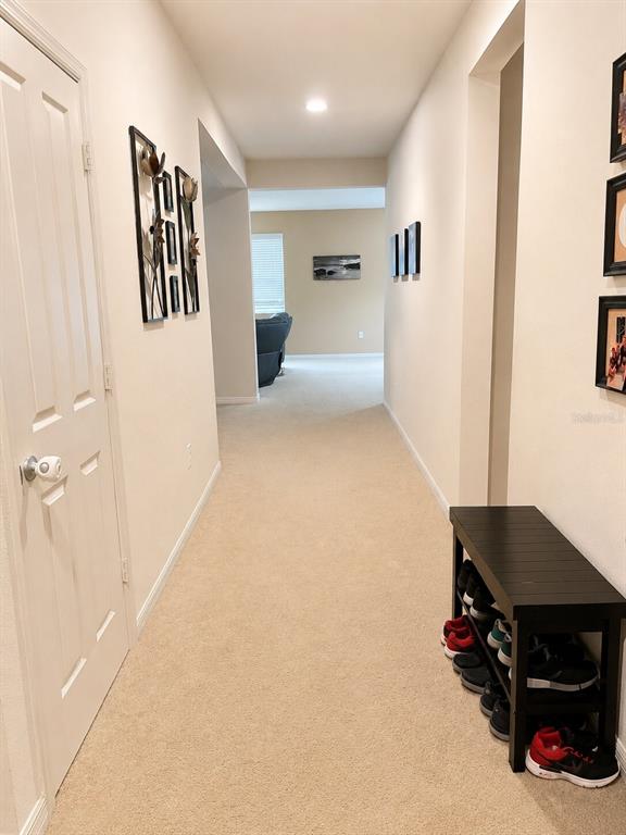 A carpeted hallway leads to an open living area, featuring a shoe rack and wall art — 2809 SHELBURNE WAY, ST CLOUD, FL