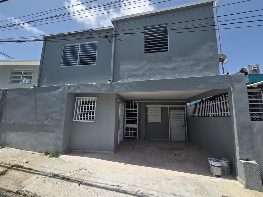 A two-story gray house features a covered carport, security bars on windows, and tiled flooring — Hato Rey GARDEL #28, SAN JUAN, PR