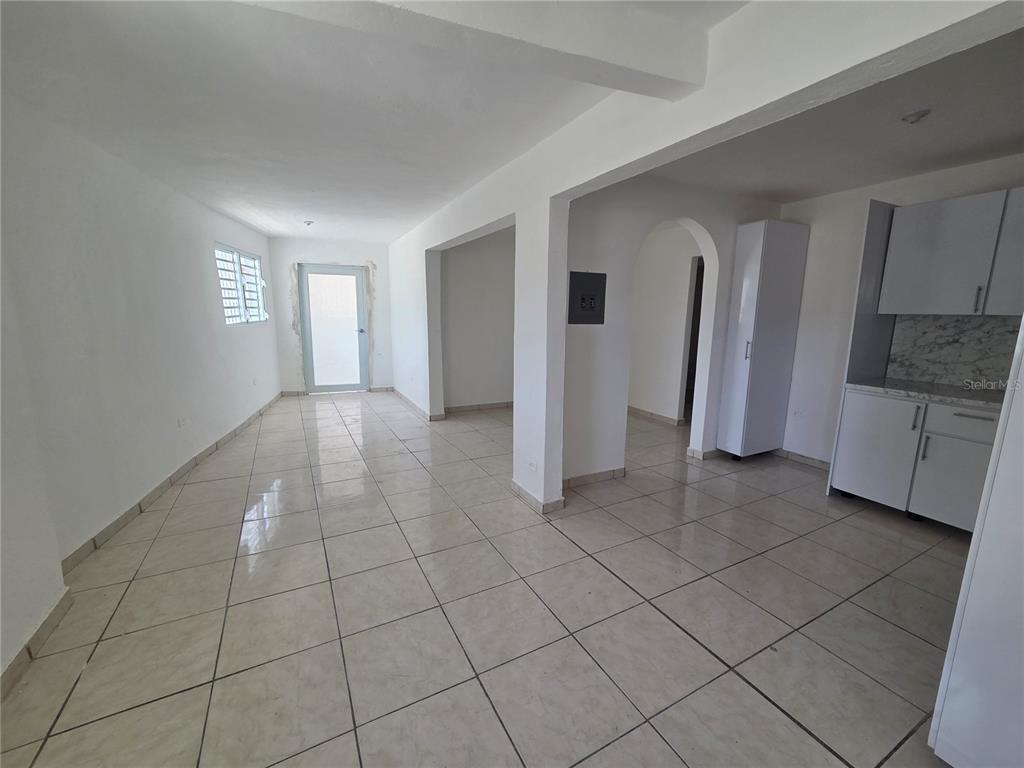 An open-concept living area with white walls, tiled floors, and an adjacent kitchen — Hato Rey GARDEL #28, SAN JUAN, PR