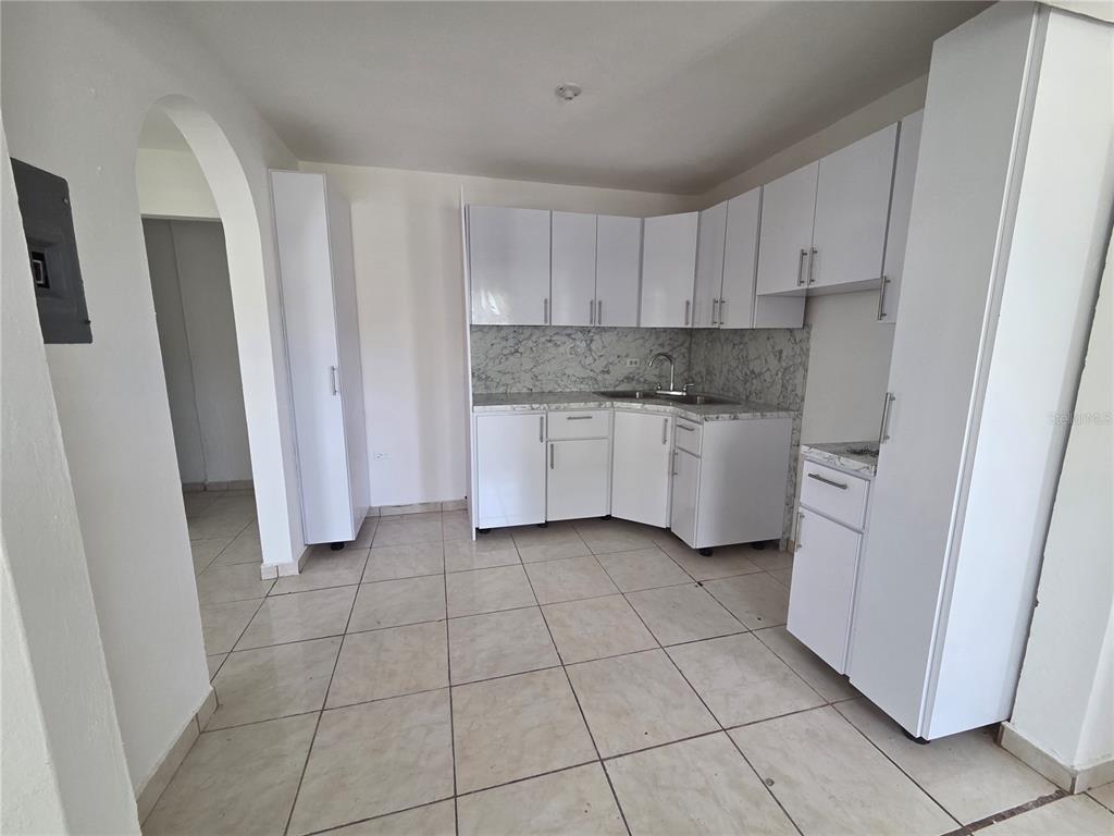 A kitchen features white cabinets, a marble-patterned backsplash, and light-colored tile flooring — Hato Rey GARDEL #28, SAN JUAN, PR