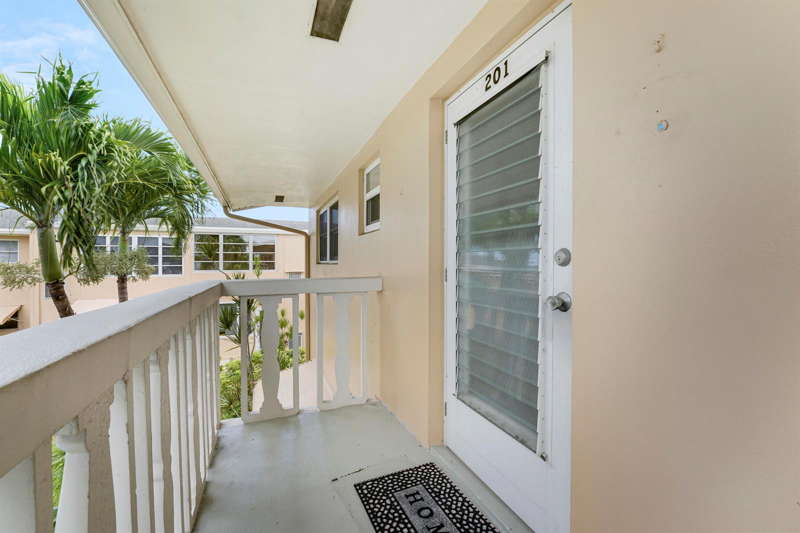 An exterior balcony with a white railing leads to a door labeled 201 — 2132 NE 1st Way # 201, Boynton Beach FL 33435, BOYNTON BEACH, FL