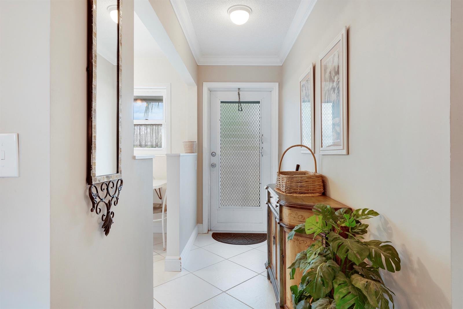 A brightly lit entryway features white tile flooring, a wooden cabinet, and a front door — 2132 NE 1st Way # 201, Boynton Beach FL 33435, BOYNTON BEACH, FL
