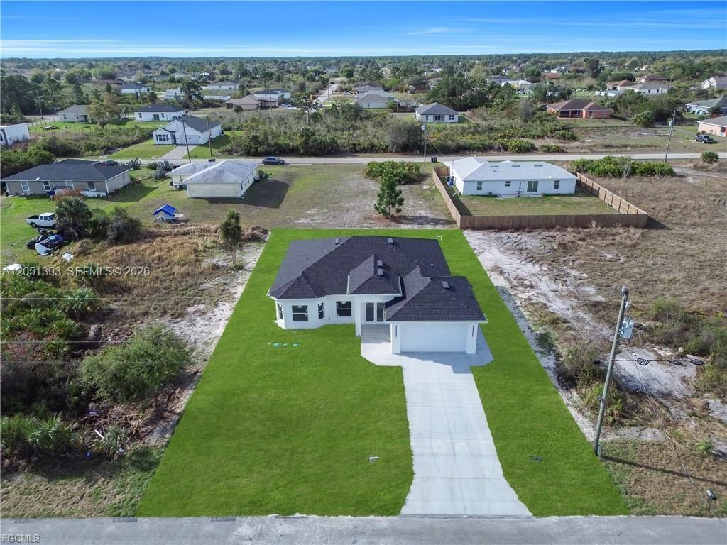 An aerial view shows a single-story house with a dark roof and a concrete driveway — 2909 63rd St W, Lehigh Acres FL 33971, LEHIGH ACRES, FL