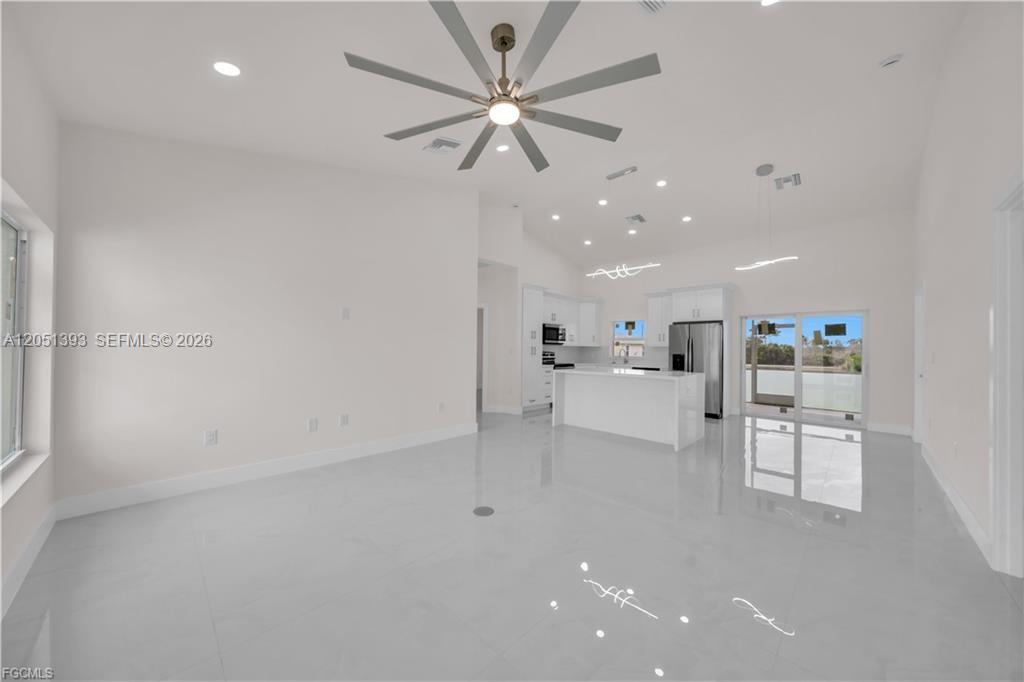 A bright, open-concept kitchen and living area features white cabinetry, tile flooring, and a ceiling fan — 2909 63rd St W, Lehigh Acres FL 33971, LEHIGH ACRES, FL