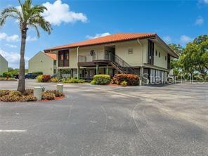 A two-story apartment building with a tan exterior and a palm tree in the foreground — 1515 PINELLAS BAYWAY S UNIT 40, ST PETERSBURG, FL