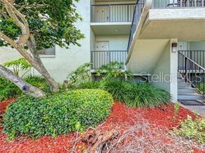 An exterior view of a multi-story building with a staircase, balconies, and landscaped garden beds — 1515 PINELLAS BAYWAY S UNIT 40, ST PETERSBURG, FL