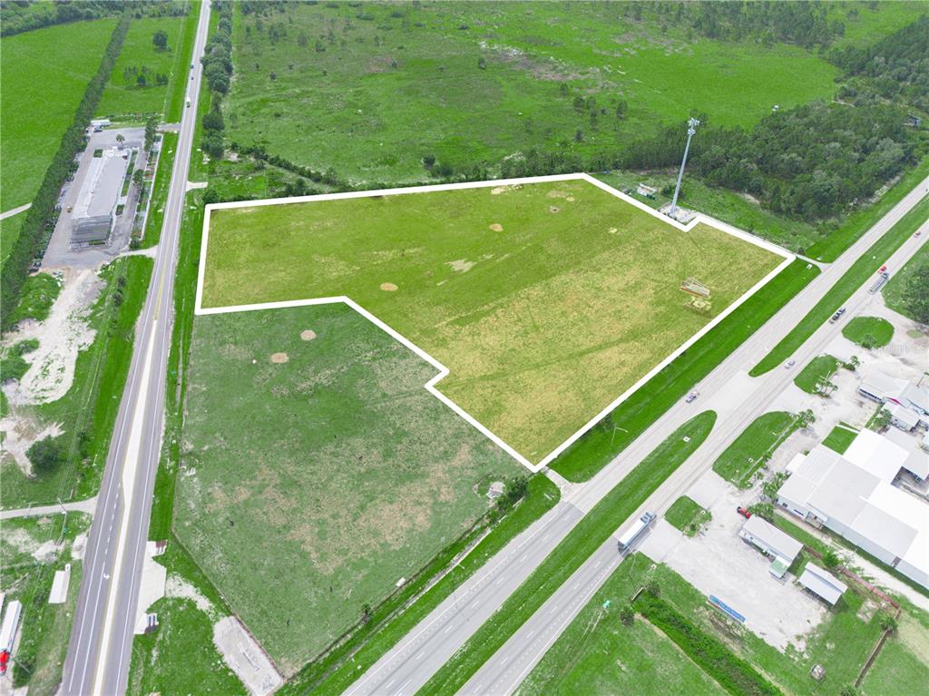 An aerial view shows a large, vacant grassy lot outlined in white between two roads — 7316 HWY 27, FROSTPROOF, FL