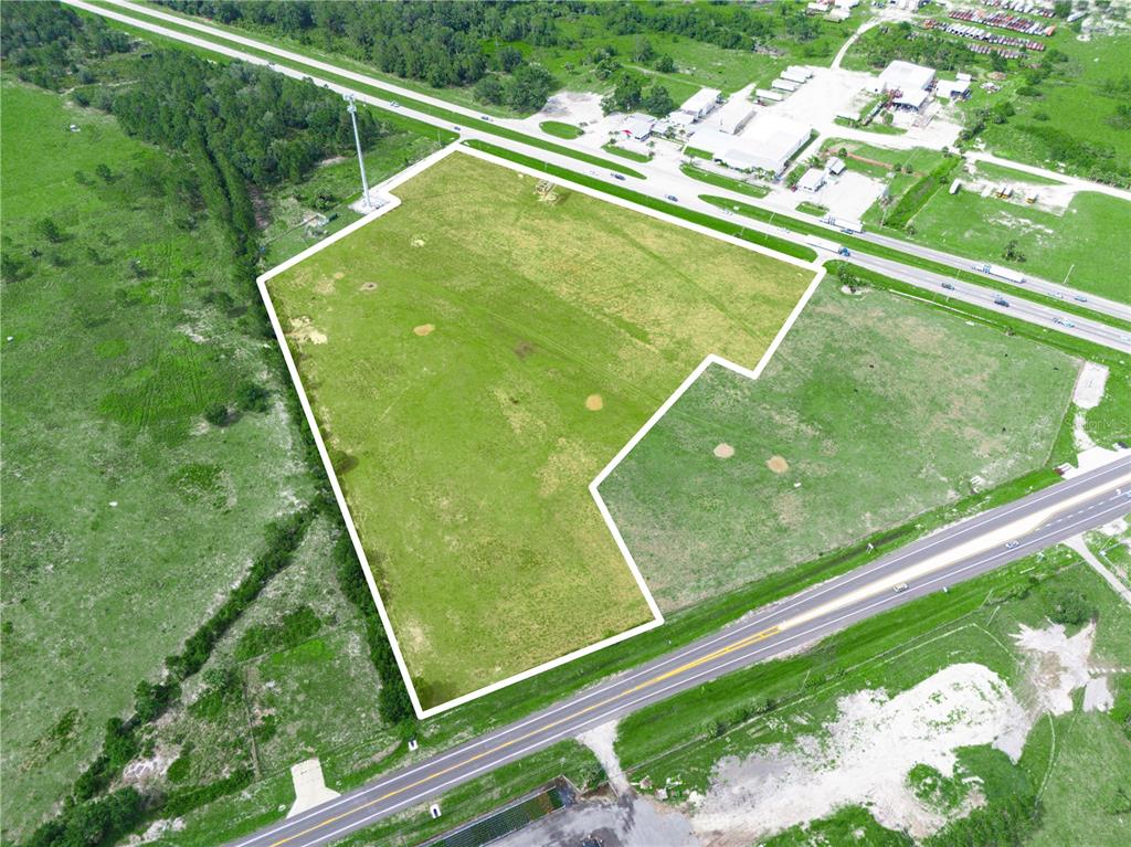 An aerial view shows a large, vacant, irregularly shaped grassy lot bordered by two roads — 7316 HWY 27, FROSTPROOF, FL