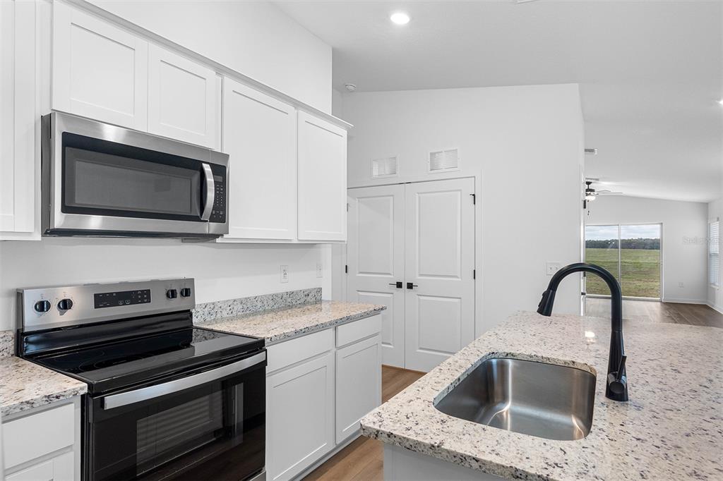 A kitchen with white cabinets, granite countertops, stainless steel appliances, and a central island — 591 BLACKTHORN DRIVE, LAKELAND, FL