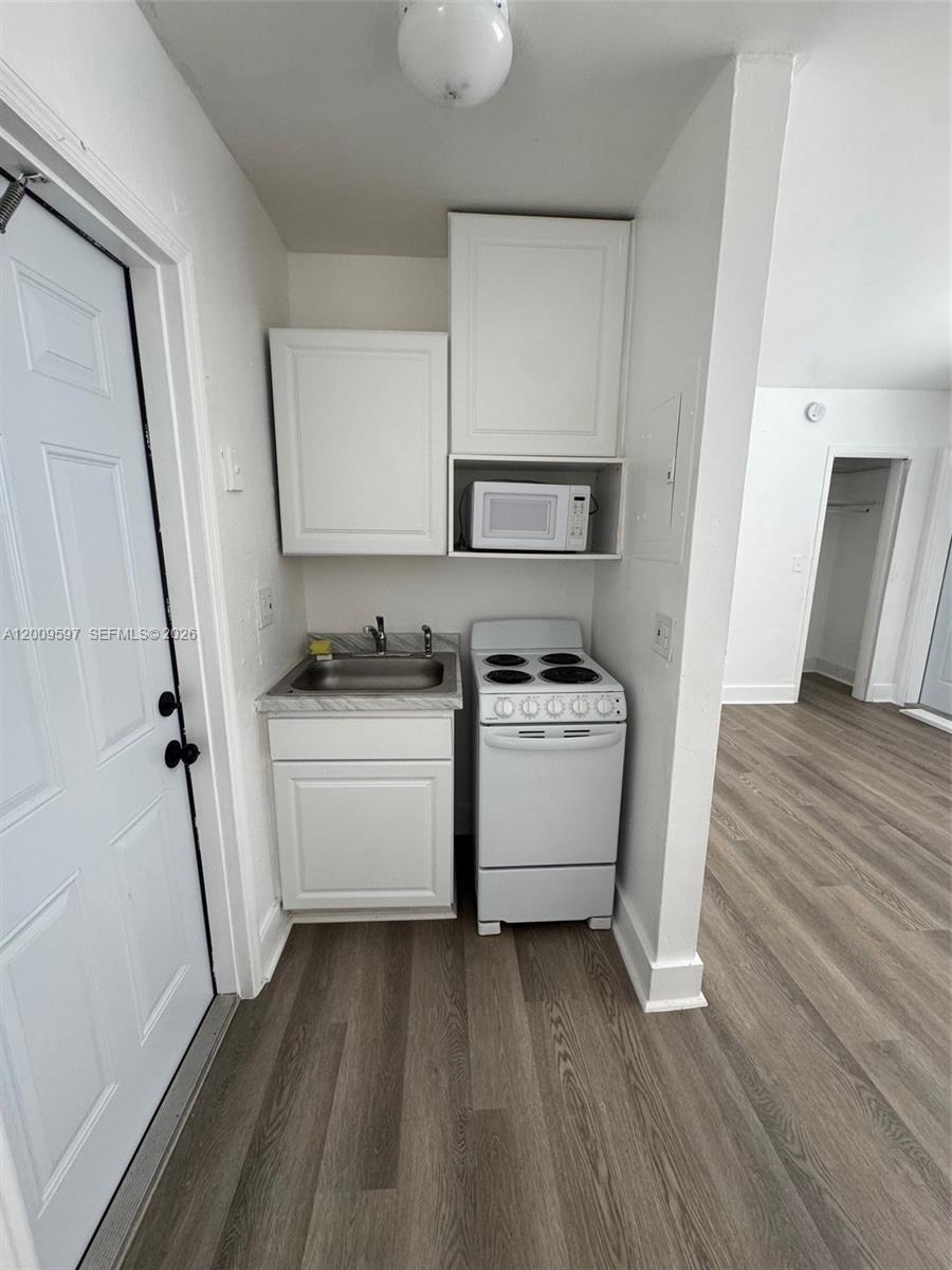 A small kitchenette features a sink, white stove, microwave, and upper cabinets — 240 NW 64 str # 4, Miami FL 33150, MIAMI, FL