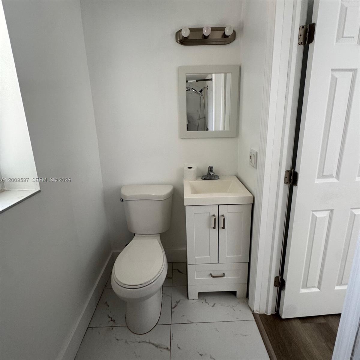 A small bathroom features a white vanity, a toilet, and a wall-mounted mirror — 240 NW 64 str # 4, Miami FL 33150, MIAMI, FL