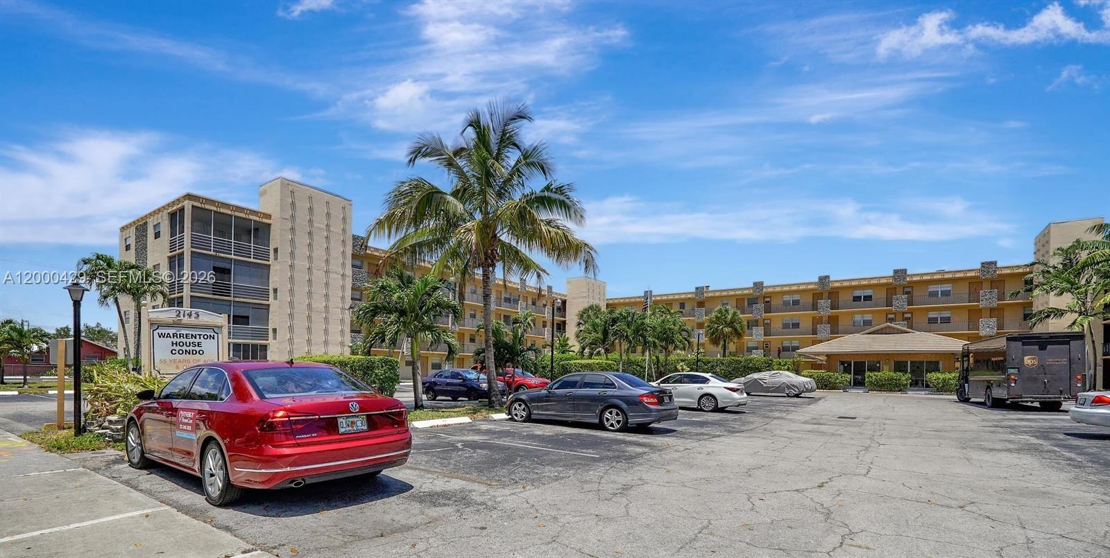 A red sedan is parked in front of a multi-story apartment complex with palm trees — 2145 Pierce St # 326, Hollywood FL 33020, HOLLYWOOD, FL