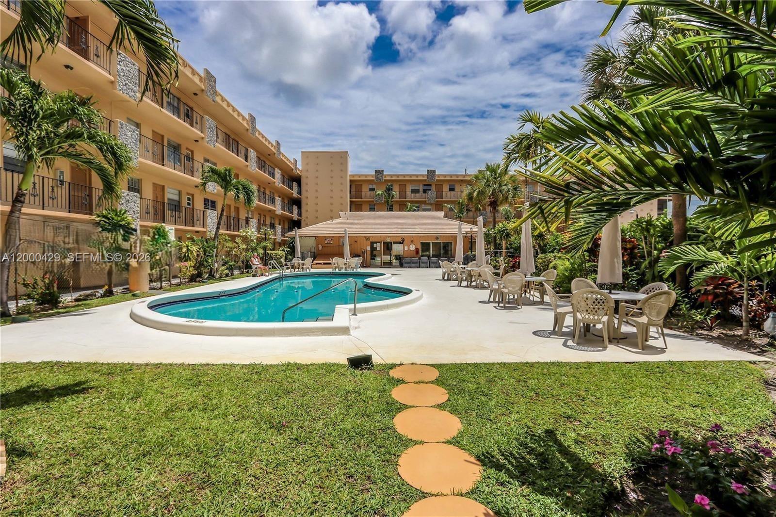 An outdoor swimming pool is surrounded by a patio, lounge chairs, and multi-story apartment buildings — 2145 Pierce St # 326, Hollywood FL 33020, HOLLYWOOD, FL