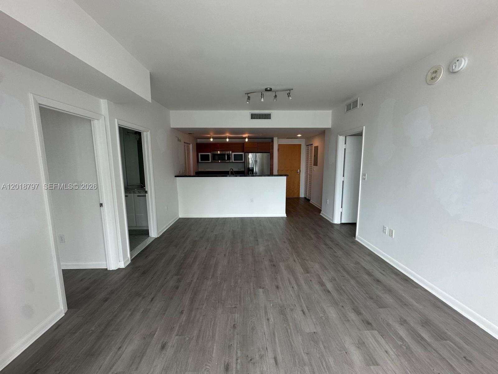 An open-concept living area features gray wood-look flooring and a kitchen with dark cabinetry — 244 Biscayne Blvd # 1910, Miami FL 33132, MIAMI, FL