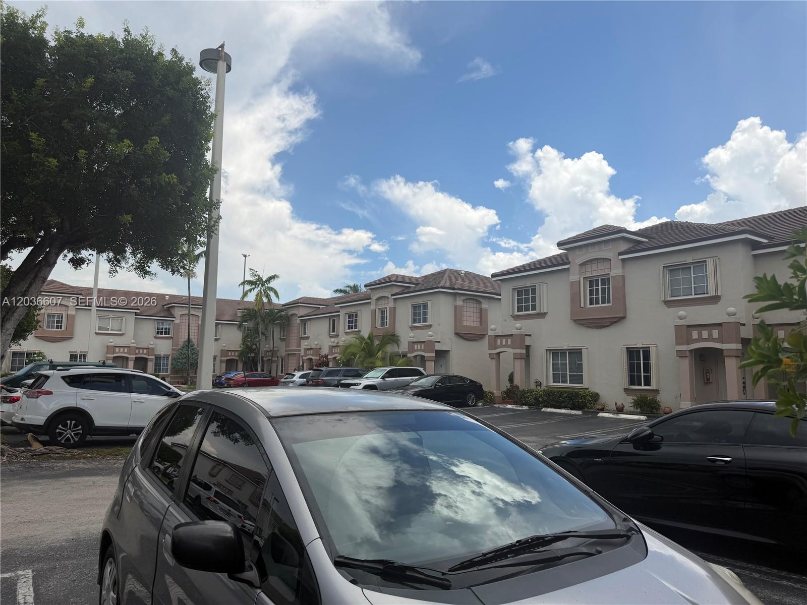 A parking lot sits in front of a row of two-story residential townhouses — 8340 NW 10th St # 1G, Miami FL 33126, MIAMI, FL