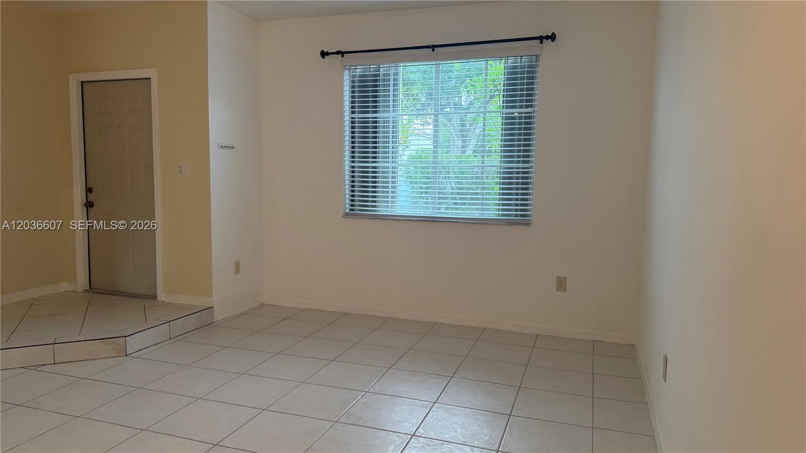 An empty room features white walls, light-colored tile flooring, and a window with blinds — 8340 NW 10th St # 1G, Miami FL 33126, MIAMI, FL