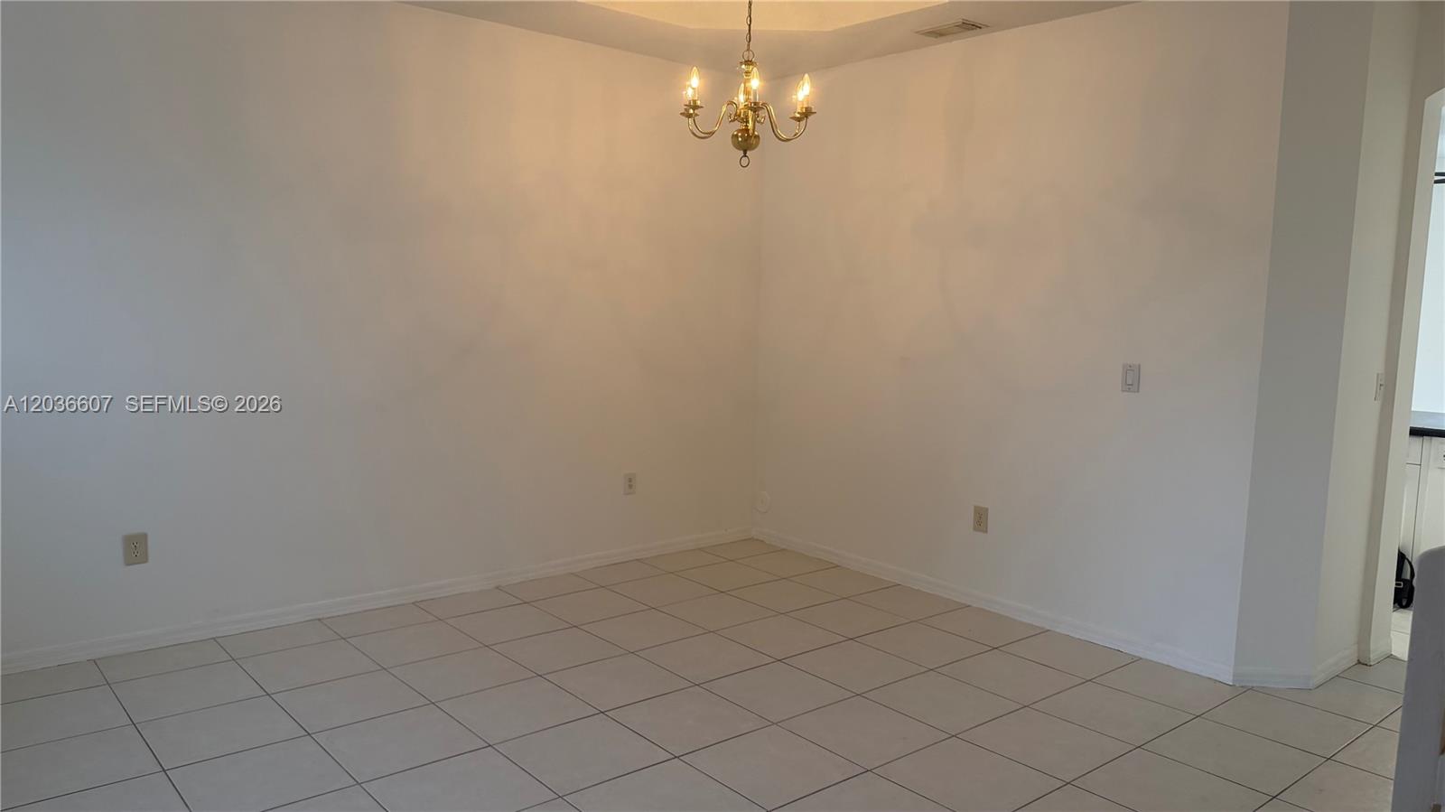 A dining area features white walls, a brass chandelier, and light-colored square floor tiles — 8340 NW 10th St # 1G, Miami FL 33126, MIAMI, FL