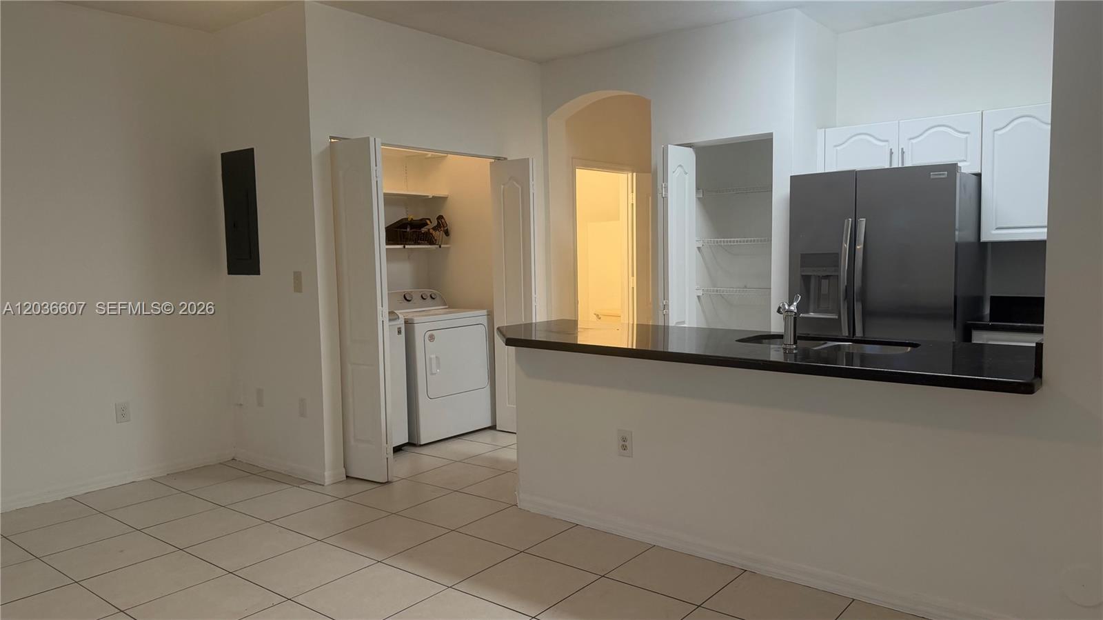 A kitchen with a breakfast bar, stainless steel refrigerator, and an adjacent laundry closet — 8340 NW 10th St # 1G, Miami FL 33126, MIAMI, FL