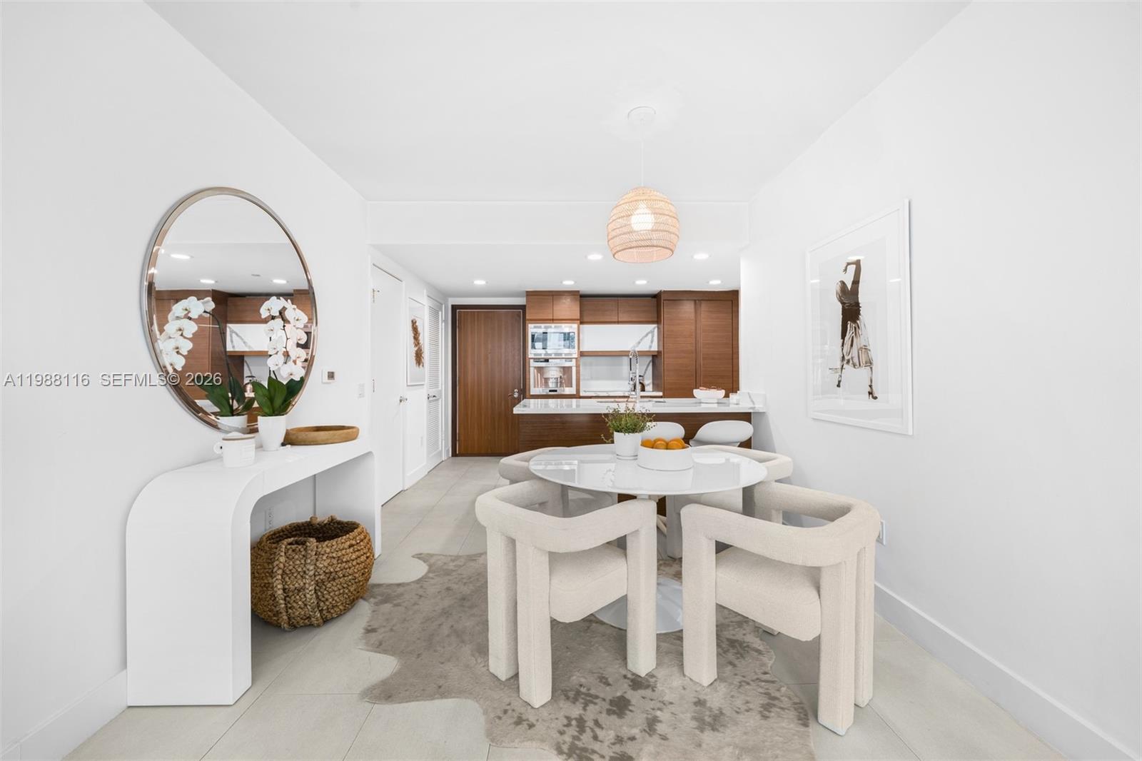 A dining area features a round white table, four chairs, and a white console table — 5875 Collins Ave # 906, Miami Beach FL 33140, MIAMI BEACH, FL