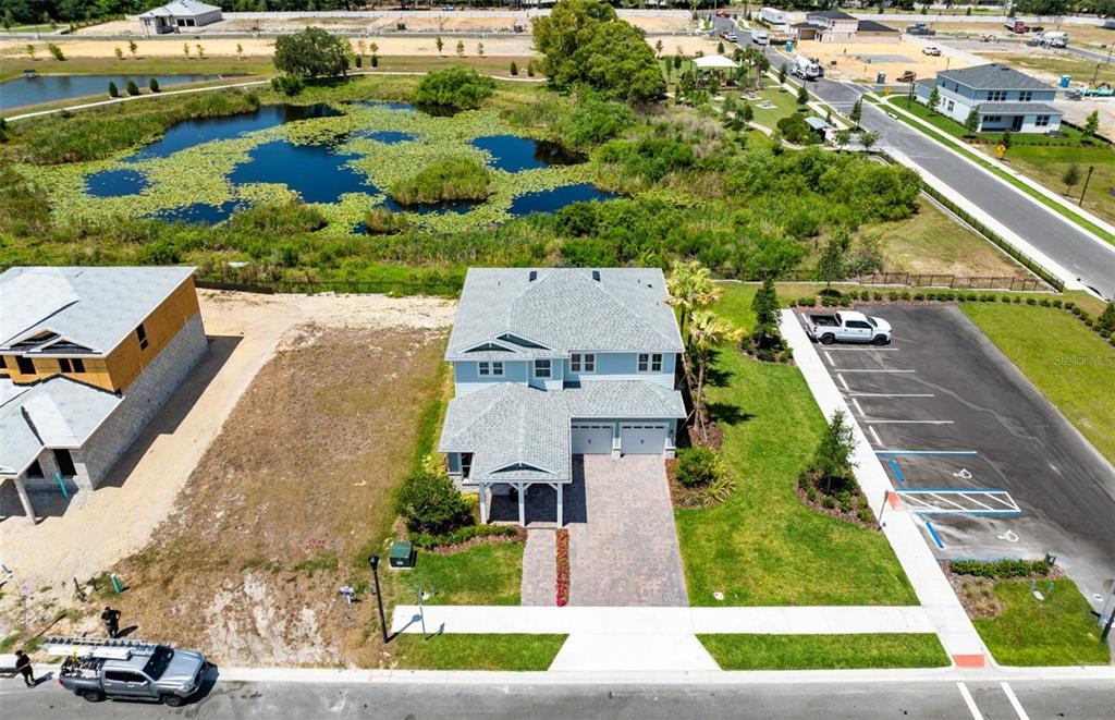 An aerial view shows a two-story house with a paved driveway next to a pond — 403 WINTER GROVE BOULEVARD, WINTER GARDEN, FL