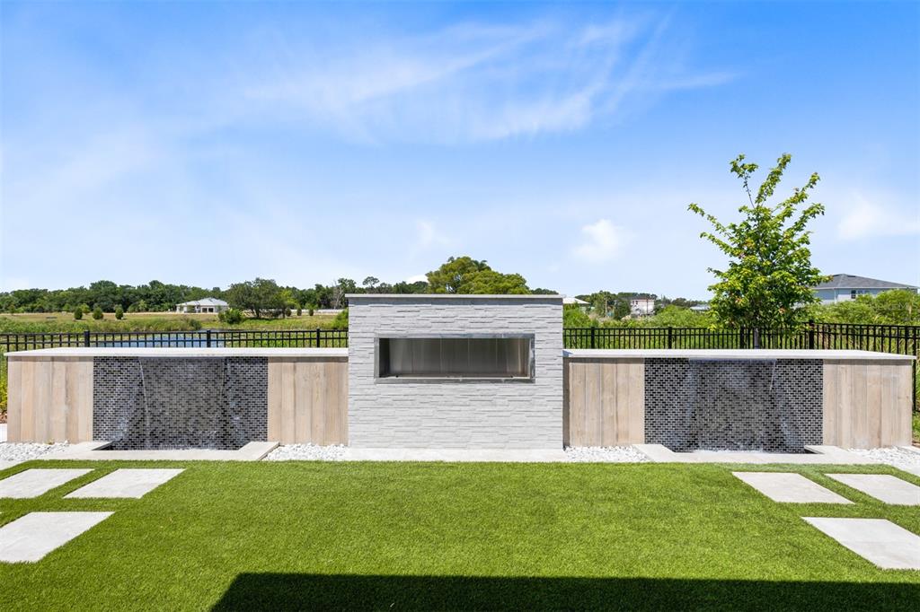 A backyard features a stone fireplace flanked by two water features and a grassy lawn — 403 WINTER GROVE BOULEVARD, WINTER GARDEN, FL