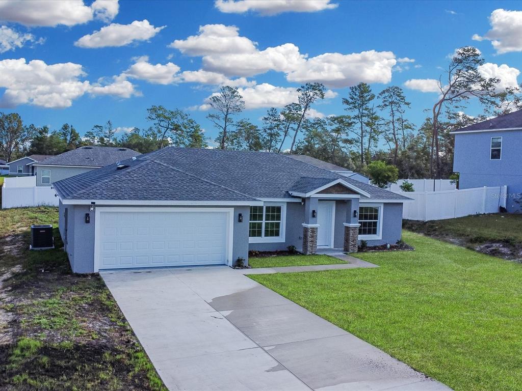 A single-story gray house with a two-car garage and a white vinyl fence — 16619 SW 31ST CIRCLE, OCALA, FL