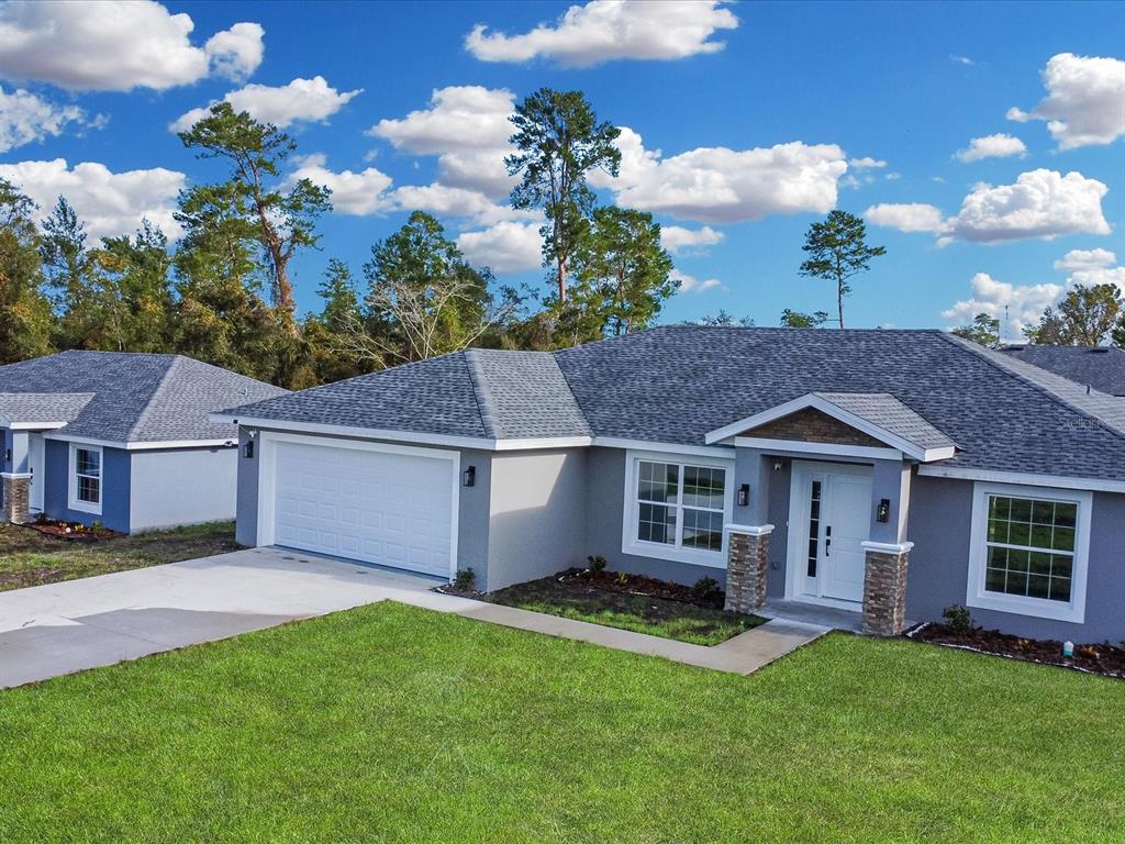 A single-story gray house with a two-car garage and a stone-accented entryway — 16619 SW 31ST CIRCLE, OCALA, FL