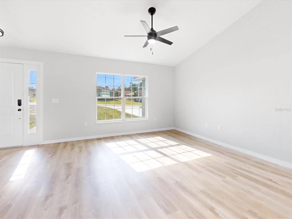 An empty room with light wood-look flooring, white walls, a ceiling fan, and a window — 16619 SW 31ST CIRCLE, OCALA, FL