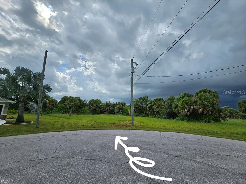 A vacant, grassy residential lot viewed from a paved cul-de-sac under a cloudy sky — 105 ISLAND COURT, ROTONDA WEST, FL