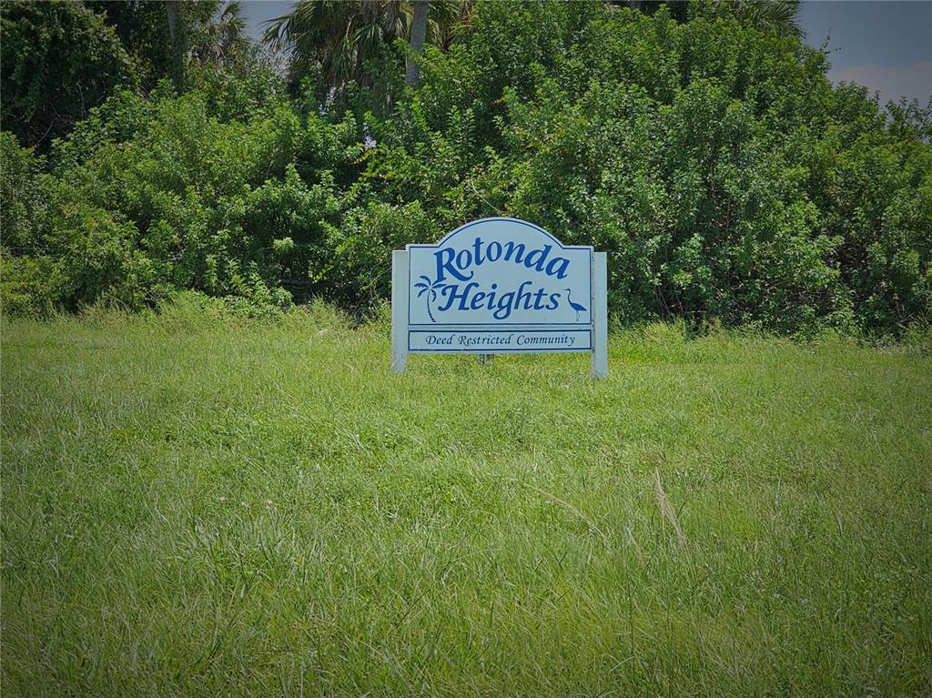 A sign for Rotonda Heights stands in a grassy field in front of dense trees — 105 ISLAND COURT, ROTONDA WEST, FL