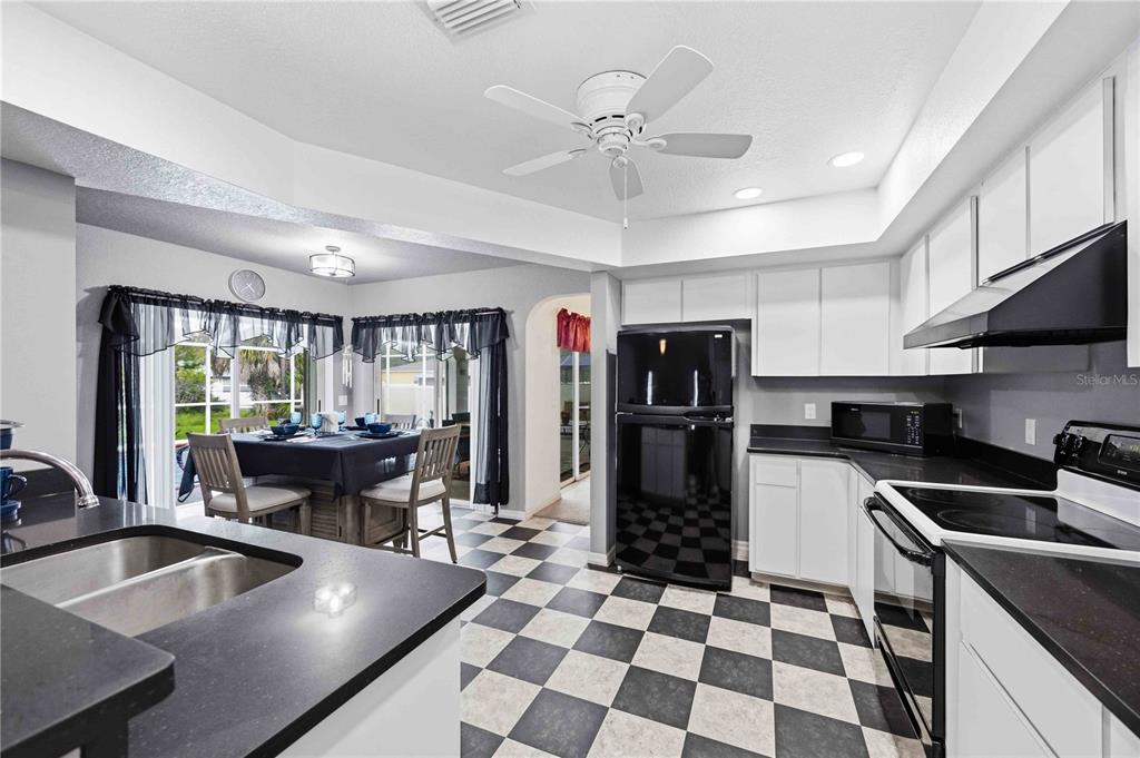 A kitchen with black countertops, white cabinets, and a black-and-white checkered floor — 273 CICERO STREET NW, PORT CHARLOTTE, FL
