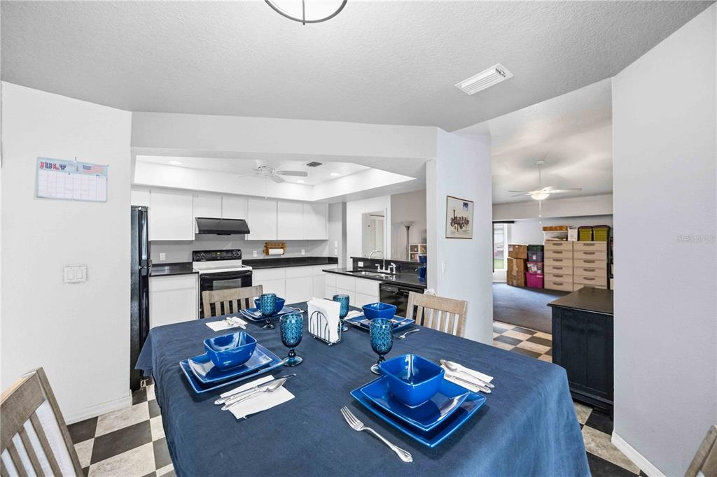 A dining area with a blue tablecloth sits in front of a white kitchen — 273 CICERO STREET NW, PORT CHARLOTTE, FL