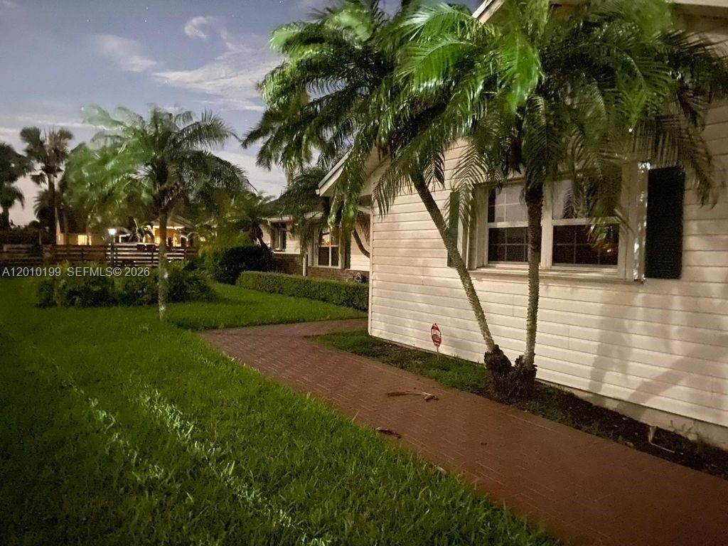 A white house exterior features a brick walkway and palm trees at night — 29490 SW 193 AVE, Homestead FL 33030, HOMESTEAD, FL