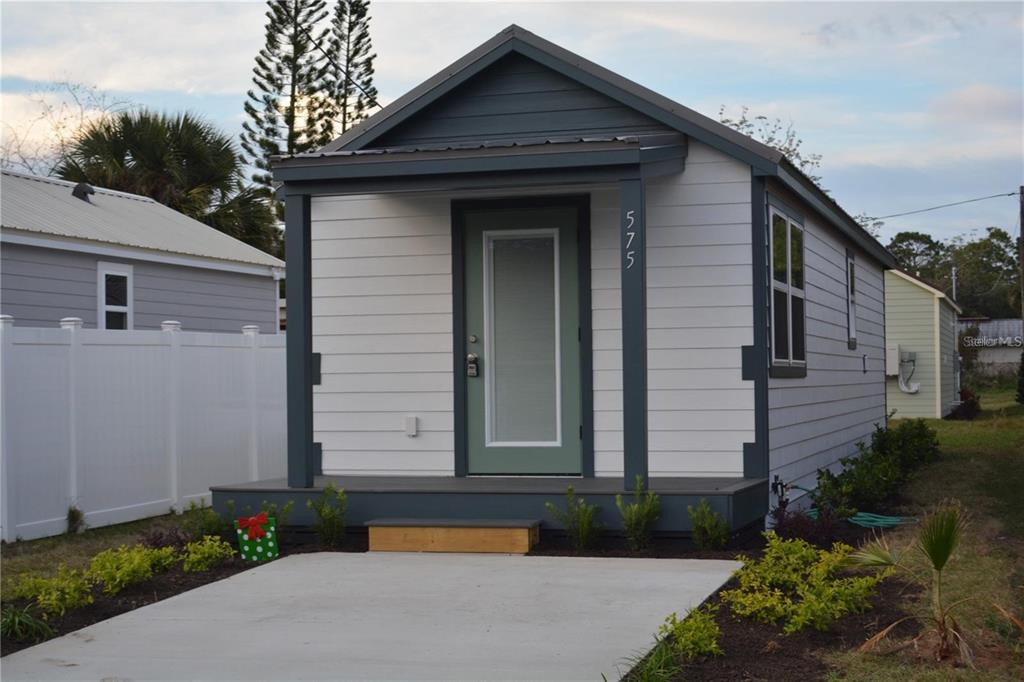 A small, white, single-story house with a dark gray porch and a green front door — 575 2ND STREET, OVIEDO, FL